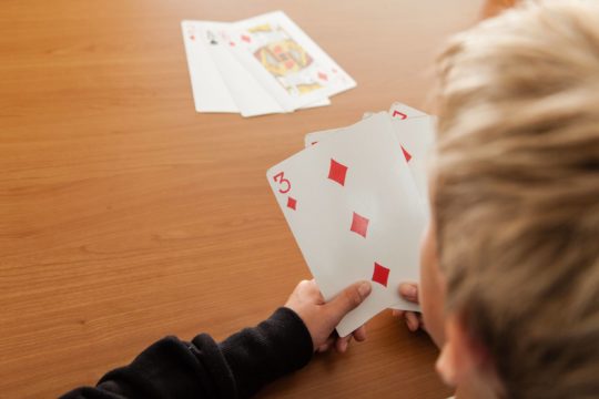 Young boy holding playing cards
